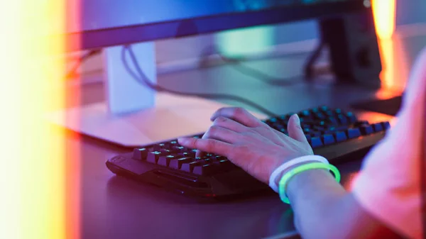 Close-up nas mãos do jogador jogando no jogo de vídeo em um teclado e usando o mouse. Néon Arcade elegante vermelho brilhante, rosa, violeta, cores verdes. — Fotografia de Stock