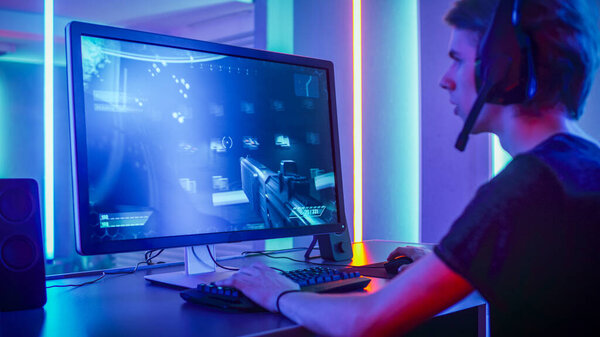 Shot of the Professional Gamer Playing in First-Person Shooter Online Video Game on His Personal Computer. Room Lit by Neon Lights in Retro Arcade Style. Online Cyber e-Sport Internet Championship.