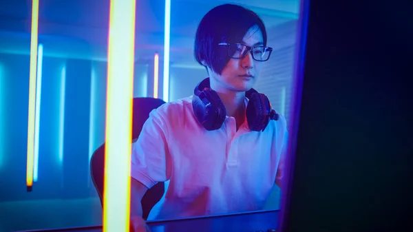 Профессиональный восточноазиатский геймер играет в онлайн видеоигру на своем персональном компьютере. Room Lit by Neon Lights in Retro Arcade Style. Чемпионат мира по киберспорту. — стоковое фото
