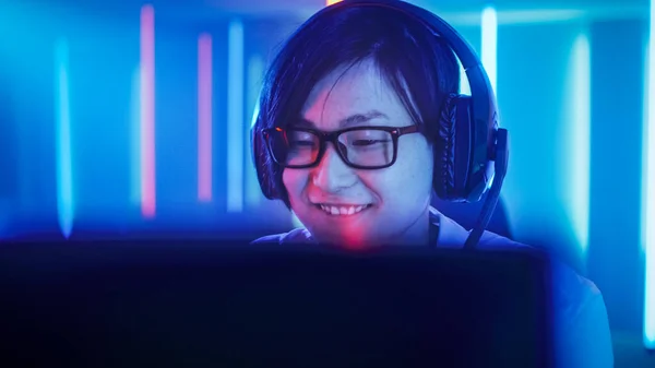 Jogador profissional do Leste Asiático jogando em jogo de vídeo online em seu computador pessoal. Ele está a sorrir. Quarto Lit by Neon Lights em estilo Retro Arcade. Cyber Sport Championship. — Fotografia de Stock