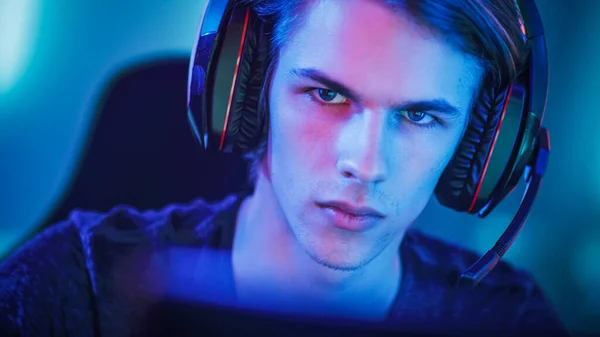 Portrait of the Young Handsome Pro Gamer Playing in Online Video Game, talks with Team Players through Microphone. Neon Colored Room. e-Sport Cyber Games Internet Championship. — Stock Photo, Image