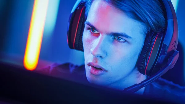 Portrait of the Young Handsome Pro Gamer Playing in Online Video Game, talks with Team Players through Microphone. Neon Colored Room. e-Sport Cyber Games Internet Championship. — Stock Photo, Image