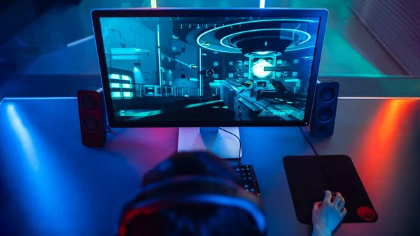 Высокоугольный выстрел в голову Гарета Бэйла, играющего в онлайн-игру "Стрелок" на своем персональном компьютере. Room Lit by Neon Limp in Retro Arcade Style. — стоковое фото
