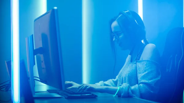 Mooi professioneel gamer meisje speelt in First Person Shooter Video Game op haar personal computer, Casual schattig Geek dragen van glazen, gesprekken met haar teamgenoten. Neon Lights Kamer. eSport Cyber spelletjes — Stockfoto