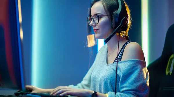 Bella ragazza giocatore professionista che gioca in prima persona sparatutto video gioco online sul suo personal computer. Casual Cute Geek indossa occhiali e sorridente. Cyber e-Sport Campionato Internet. — Foto Stock