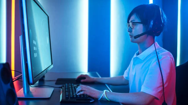 サイドビュー彼のパーソナルコンピュータ上で一人称シューティングオンラインビデオゲームで遊ぶプロのゲーマーのショット。ヘッドセットを使用している。Room Lit by Neon Lights in Retro Arcade Style。サイバースポーツ — ストック写真