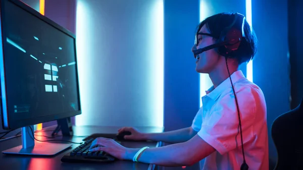 Seitenansicht eines professionellen Spielers, der in einem Ego-Shooter-Online-Videospiel auf seinem Personal Computer spielt. Er benutzt Headset. Zimmer Lit von Neon Lights im Retro Arcade Stil. Cyber-Sport — Stockfoto