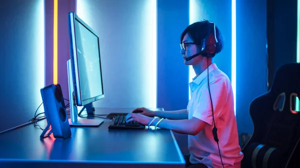 Seitenansicht eines professionellen Spielers, der in einem Ego-Shooter-Online-Videospiel auf seinem Personal Computer spielt. Er benutzt Headset. Zimmer Lit von Neon Lights im Retro Arcade Stil. Cyber-Sport — Stockfoto