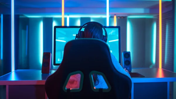 Back View of Professional Gamer Playing in First-Person Shooter Online Video Game on His Personal Computer. Room Lit by Neon Lights in Retro Arcade Style. Cyber Sport Championship. — Stock Photo, Image