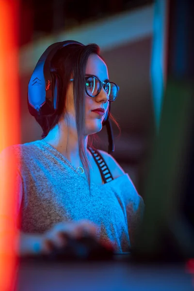 Porträtt Skott av en vacker professionell Gamer Girl spelar i First-Person Shooter Online TV-spel på hennes personliga dator. Casual Cute Geek i glasögon och prata i headset. Vertikal — Stockfoto