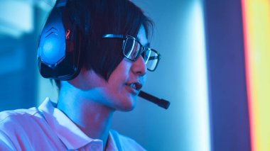 Doğu Asyalı profesyonel oyuncunun düşük açılı görüntüsü mikrofona kulaklıkla konuşuyor. Şampiyonada Arkadaşlarla ya da Takımla Oynamak.