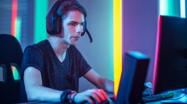 Young Pro Gamer Playing in Online Video Game, talks with Team Players through Microphone. Neon Colored Room. e-Sport Cyber Games Internet Championship. clipart