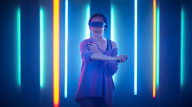 Sanal Gerçeklik Kulaklığı takan ve Joystick Kontrolörleri Tutan Güzel Genç Kız. Yaratıcı Genç Kız Sanatı Geliştirilmiş Gerçeklikle Kavradı. Online Video Oyunu oynuyorum. Neon Retro Işıkları