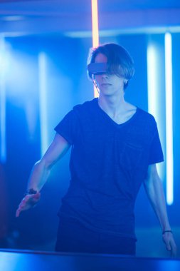 Sanal Gerçeklik Kulaklık Dansları Giyen Yakışıklı Genç Çocuk. Arka planda Cool Neon Retro Işıkları.