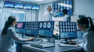 Profesyonel Bilim Adamları Ekibi Beyin Araştırma Laboratuvarı 'nda çalışıyor. Nörologlar, BT, MRI taramalarının tartıştığını ve Kişisel Bilgisayarlar üzerinde çalıştığını gösteren monitörlerle çevrelenmiş nörologlar..