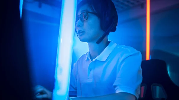 彼のパーソナルコンピュータ上のオンラインビデオゲームで遊ぶプロの東アジアのゲーマーの低角度ショット。Room Lit by Neon Lights in Retro Arcade Style。サイバースポーツ選手権. — ストック写真