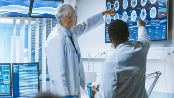 専門科学者チーム脳研究室で働いています。脳神経科医モニターに囲まれた脳神経科学者CT 、 MRIスキャンを展示し、パソコンに関するディスカッションや作業を行う. — ストック写真