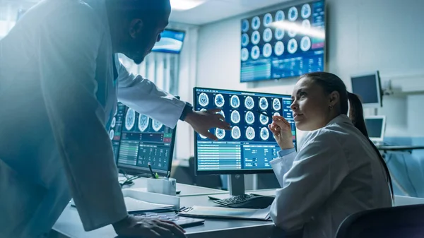 Två forskare i hjärnforskningslaboratoriet arbetar på ett projekt, med hjälp av persondator med MRI-skannrar Visa hjärnavvikelser. Neuroforskare i arbete. — Stockfoto