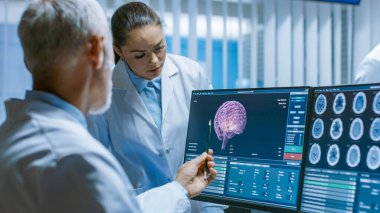 Beyin Araştırma Laboratuvarında iki tıp bilimcisi Nörofizyoloji Projesi Tümörlerle Mücadele 'de ilerleme kaydediyor. Nörologlar MRI ile Kişisel Bilgisayar kullanıyor, CT taramaları Beyin Resimlerini gösteriyor.