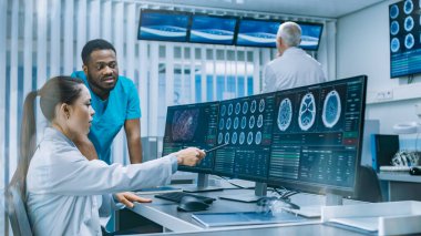 Tıbbi Bilimci ve Cerrah, Laboratuvardaki Kişisel Bilgisayar 'da CT Beyin Taramasını Tartışıyor. Nörologlar Nörolojik Araştırma Merkezi 'nde beyin tümörü tedavisi üzerinde çalışıyorlar..