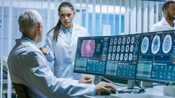 Twee medische wetenschappers in het laboratorium voor hersenonderzoek bespreken de voortgang van het neurofysiologische project tegen tumoren. Neurowetenschappers gebruiken personal computer met MRI, CT-scans tonen hersenbeelden. — Stockfoto