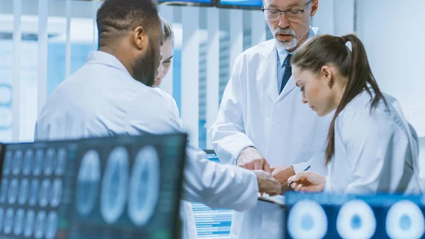 Computerbildschirm mit MRT, CT-Bildern des Gehirns. Im Hintergrundgespräch des Teams von Medizinern im Labor für Hirnforschung. Neurologen diskutieren. — Stockfoto