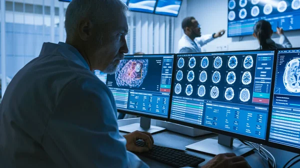 Over de schouder Shot van Senior Medical Scientist Werken met CT Brain Scan Beelden op een personal computer in het laboratorium. Neurologen in het onderzoekscentrum werken aan Hersentumor Cure. — Stockfoto