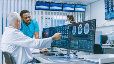 Tıbbi Bilimci ve Cerrah, Laboratuvardaki Kişisel Bilgisayar 'da CT MRI Beyin Taraması Görüntülerini tartışıyorlar. Nörologlar Nörolojik Araştırma Merkezi 'nde beyin tümörü tedavisi üzerinde çalışıyorlar..