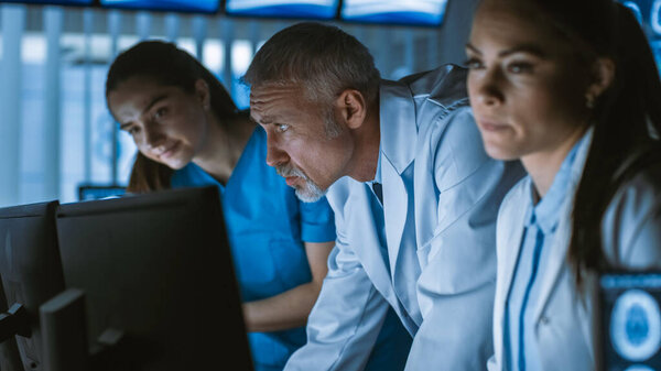 Diverse Team of Medical Scientists Solve Problems and Point at Computer Screens Showing CT, MRI Scans. Neurologists Neuroscientists Working in Brain Research Laboratory.