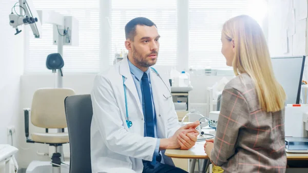 På läkarmottagningen pratar doktorn med en vacker blond kvinna. Samråd med hälso- och sjukvårdspersonal på det ljusa moderna kontoret. — Stockfoto