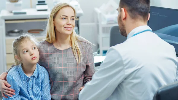 Moeder met lief klein meisje bezoek vriendelijke kinderarts. Dokter praat met hen na grondig onderzoek. Brightand Modern Medical Office. — Stockfoto