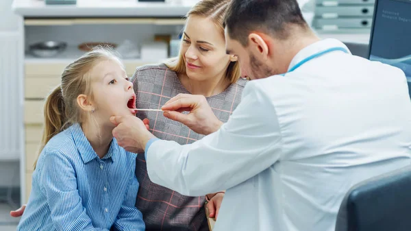 Moeder met lief klein meisje bezoek vriendelijke kinderarts. Dokter praat met hen na grondig onderzoek. Brightand Modern Medical Office. — Stockfoto