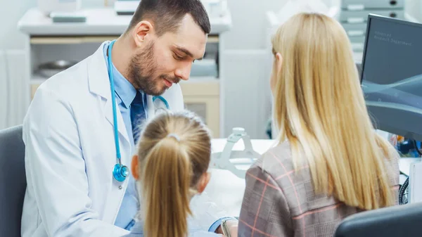 Moeder met haar schattige kleine meisje hebben artsen aanstelling. Vriendelijke kinderarts glimlacht en schrijft recepten van de ziekte. Bureau voor Moderne en Heldere Artsen. — Stockfoto