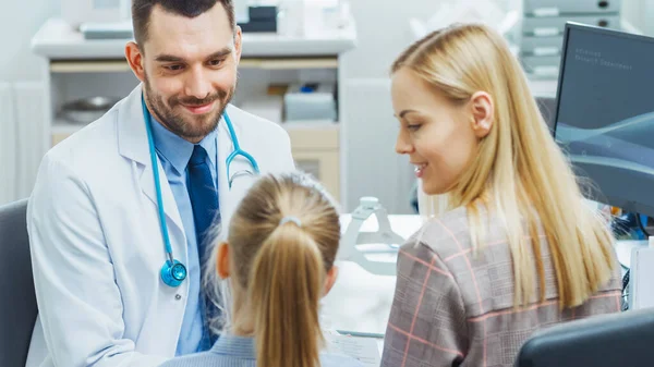 Freundliche Ärztin spricht mit süßem kleinen Mädchen, das mit ihrer Mutter zu einem Termin kam. Gesundes Kind mit glücklichen Eltern. Arbeit im Gesundheitswesen. — Stockfoto