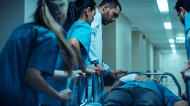 Acil Durum Departmanı: Doktorlar, Hemşireler ve Cerrahlar Hastane Koridorlarında Sedyede Yatan Yaralı Hastayı Taşıdı. Acilen Hastayı Ameliyathaneye Götürün..