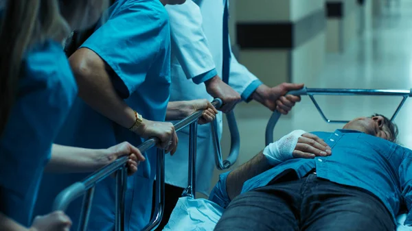 救急科:医師、看護師、外科医が手術室に向かって深刻な負傷者とガーニーストレッチャーをプッシュ. — ストック写真