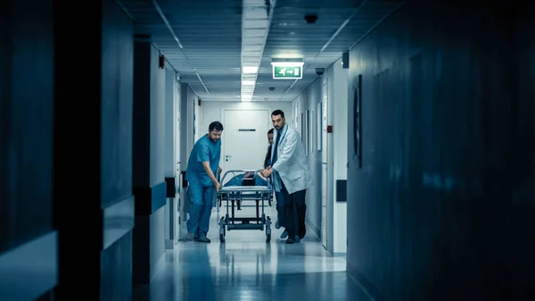 Notaufnahme: Ärzte, Krankenschwestern und Sanitäter laufen und schieben Gurney-Trage mit schwer verletztem Patienten in Richtung Operationssaal. Helles modernes Krankenhaus mit professionellem Personal. — Stockfoto