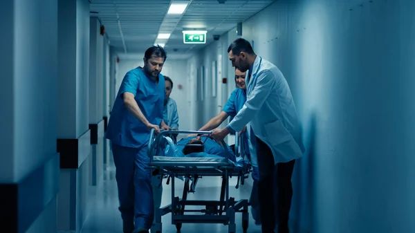 응급 부서: 의사, 간호사, 준의료 종사자들이 달려와 거니 스 트레 처를 심각하게 다친 환자와 함께 수술실로 밀어 넣는다. 전문 비서와 함께 한 현대 병원. — 스톡 사진