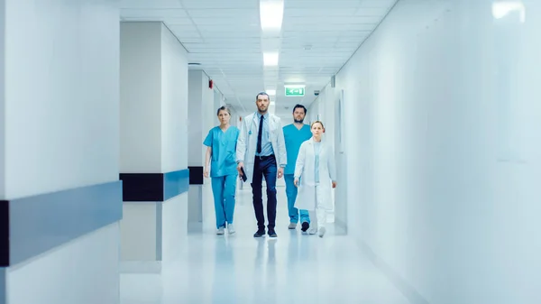 Team van artsen, chirurgen en verpleegkundigen lopen door drukke ziekenhuis hal, Ze praten over patiënten, komende chirurgie en redden van levens. Schoon modern ziekenhuis met professioneel personeel. — Stockfoto