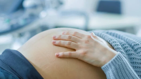 Nahaufnahme des Bauches der schwangeren Frau, während sie ihn streichelt und mit der Hand berührt. Mutter spürt, wie Baby tritt. — Stockfoto