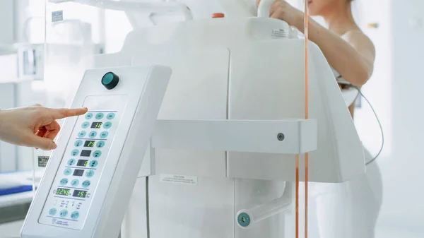 En el hospital, el tecnólogo en mamografía presiona el botón de la máquina de mamografía activando el escaneo de la paciente femenina. Amistoso médico explica la importancia de la detección de la prevención del cáncer de mama. Moderno — Foto de Stock