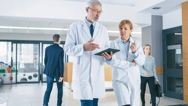 På sjukhuset, upptagen läkare prata, Använda Tablet Computer medan promenader genom byggnaden. Ny modern fullt fungerande medicinsk anläggning. — Stockfoto