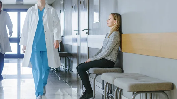 Busy Hospital Hallway. Medical Personnel, Doctors, Nurses, Surgeons Walking, Female Patient Waiting her Turn. Modern Medical Facility.