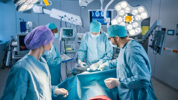 Equipo Diverso de Cirujanos Profesionales, Asistentes y Enfermeras que Realizan Cirugía Invasora a un Paciente en la Sala de Operaciones del Hospital. Los cirujanos hablan y usan instrumentos. Real Hospital Moderno con —  Fotos de Stock