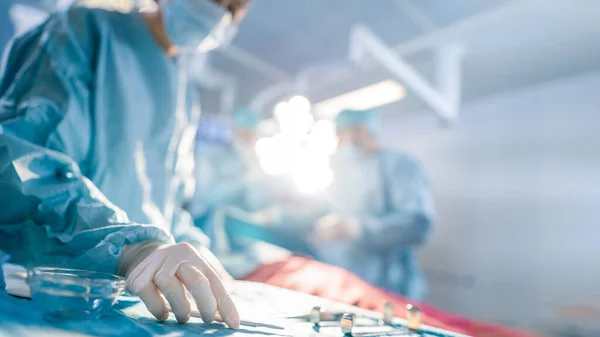 Close-up Shot in the Operating Room of Surgical Table with Instruments, Assistant Picks up Instruments for Surgeons During Operation. Surgery in Progress. Professional Medical Doctors Performing — Stock Photo, Image