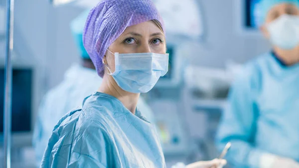 一名护士在手术室操作过程中看着相机的肖像镜头。实施外科手术的专业医生. — 图库照片