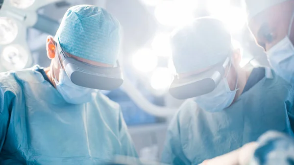 Nahaufnahme eines Chirurgen, der mit einer Augmented-Reality-Brille hochmoderne Operationen im High-Tech-Krankenhaus durchführt. Ärzte und Assistenten arbeiten im Operationssaal. — Stockfoto