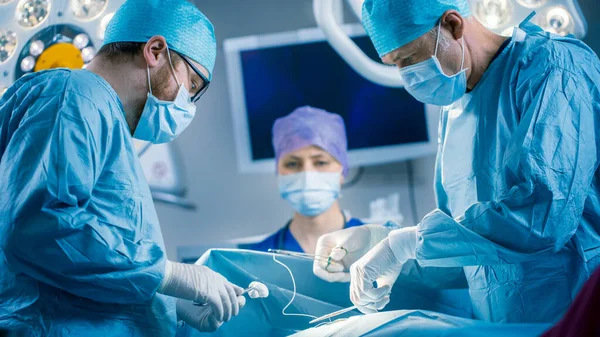 Im Operationssaal des Krankenhauses: Vielfältiges Team aus professionellen Chirurgen und Krankenschwestern vernäht Wunde nach erfolgreicher Operation. — Stockfoto