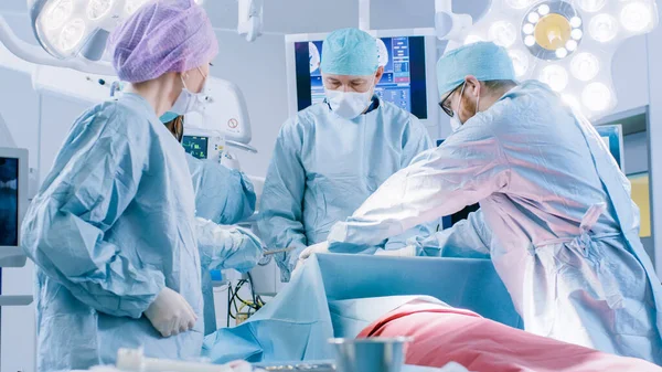 Vielfältiges Team professioneller Chirurgen, die invasive Operationen an einem Patienten im Operationssaal des Krankenhauses durchführen. Chirurg und andere Instrumente, Anästhesist überwacht Vitaldaten. — Stockfoto