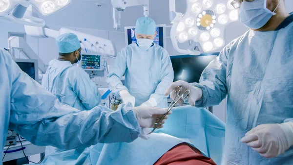 전문 외과의사의 Diverse Team of Professional Surgeons Performing Inusual Surgery on the Hospital Operating Room. 간호사는 기구를 수석 의사, 마취 전문의 인 모니터 바이탈에게 넘긴다. 완전하게 — 스톡 사진